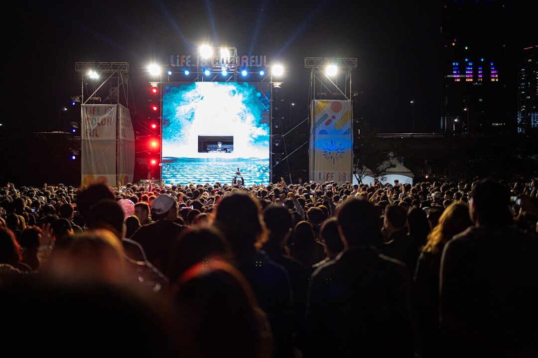 Large crowd at an outdoor concert with stage lights