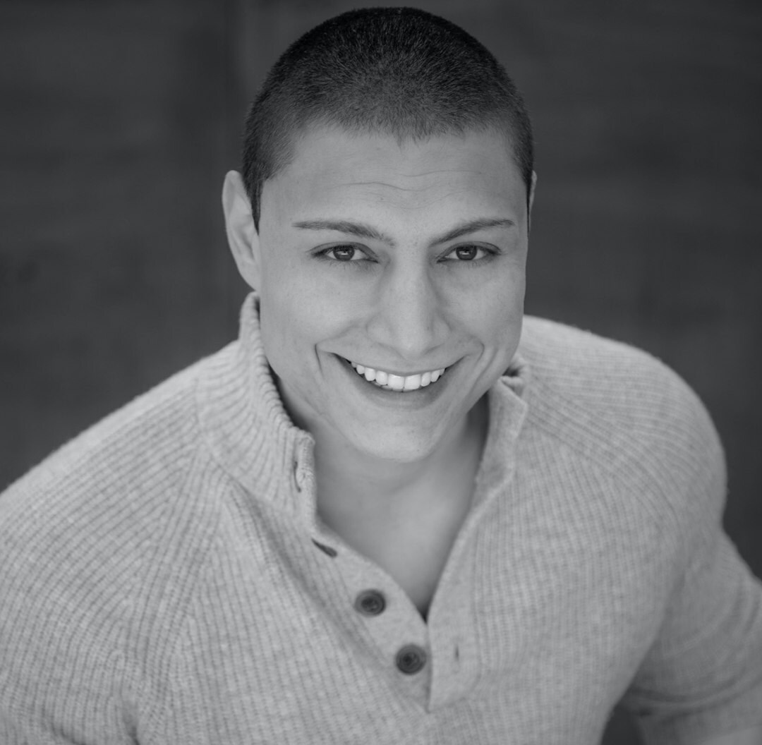 Studio portrait of a Latino man with short beard smiling